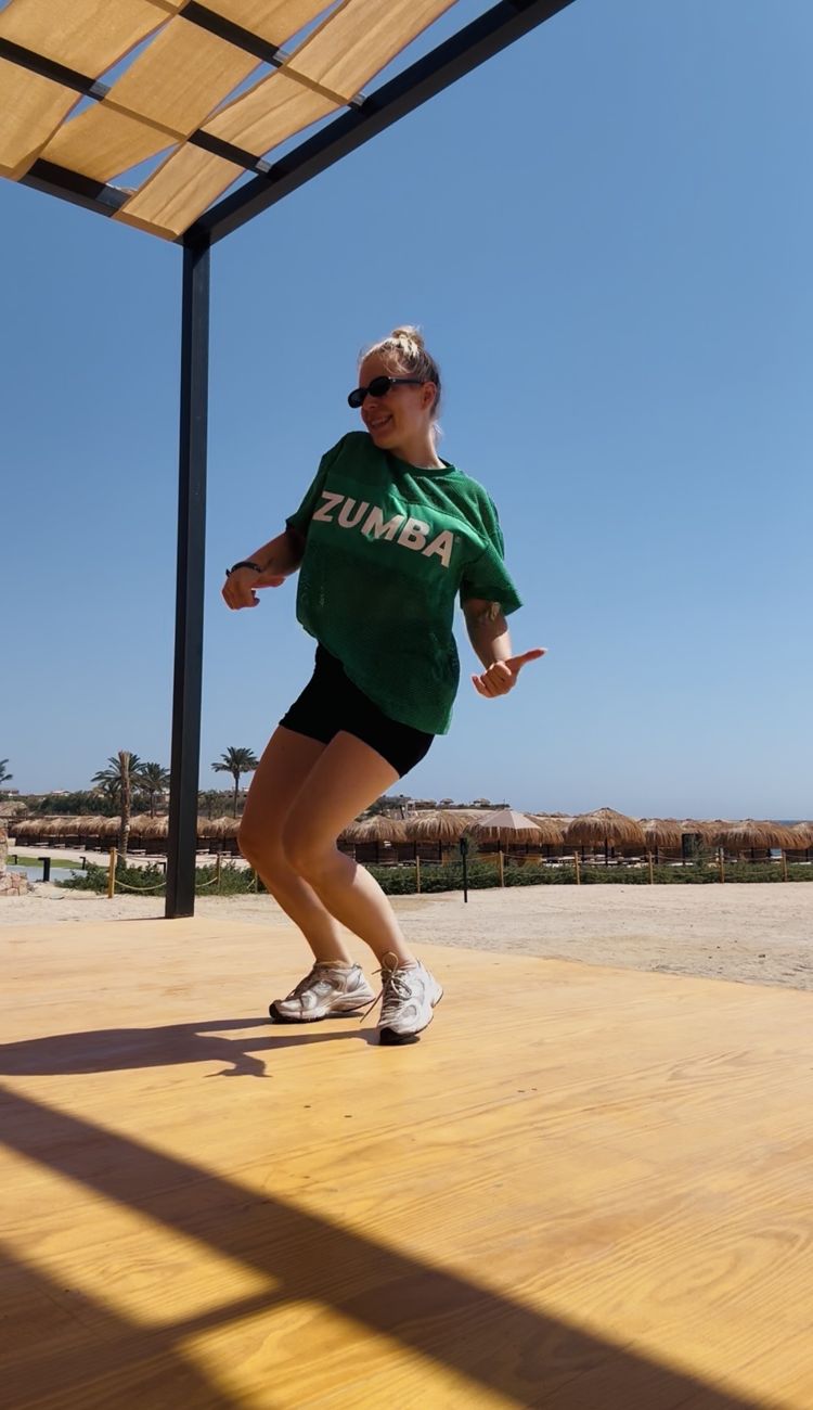 Lisa tanzt im grünen ZUMBA-Shirt auf einer Tanzfläche am Strand